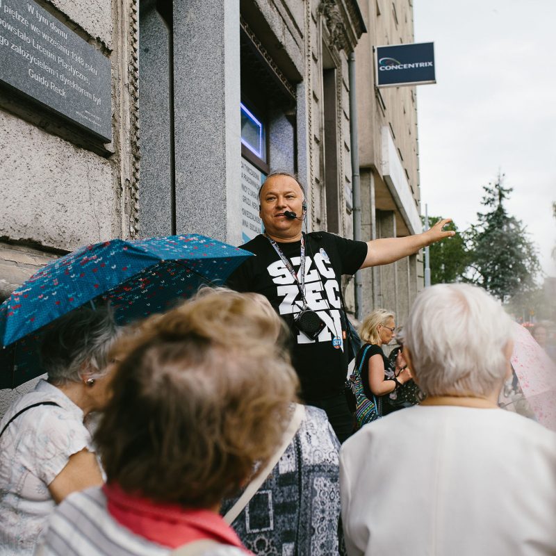 Przewodnik Tomasz Wieczorek opowiada historie uczestnikom spaceru